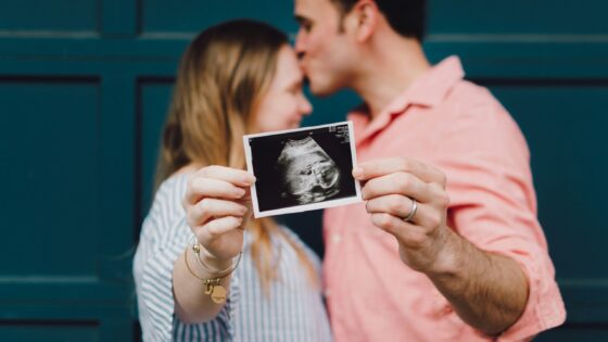 a picture of couple showing their ultraound picture of baby